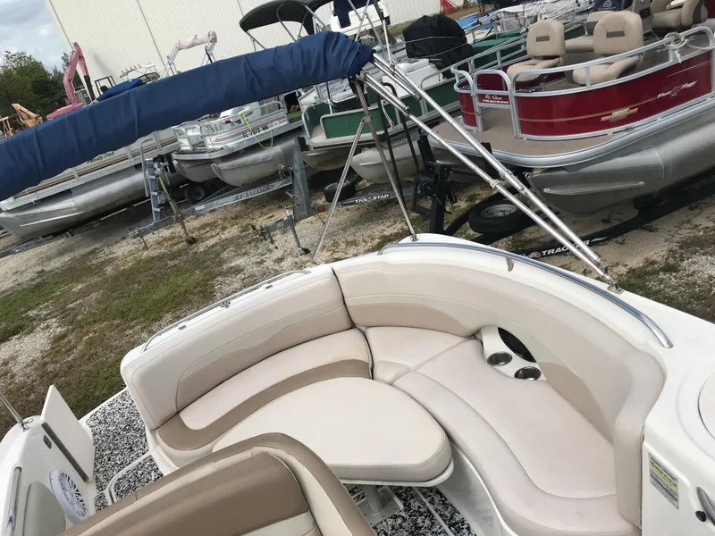 Slide: The Image of 2005 Chaparral Sunesta 252 boat interior with beige seating, parked among other boats. - 33