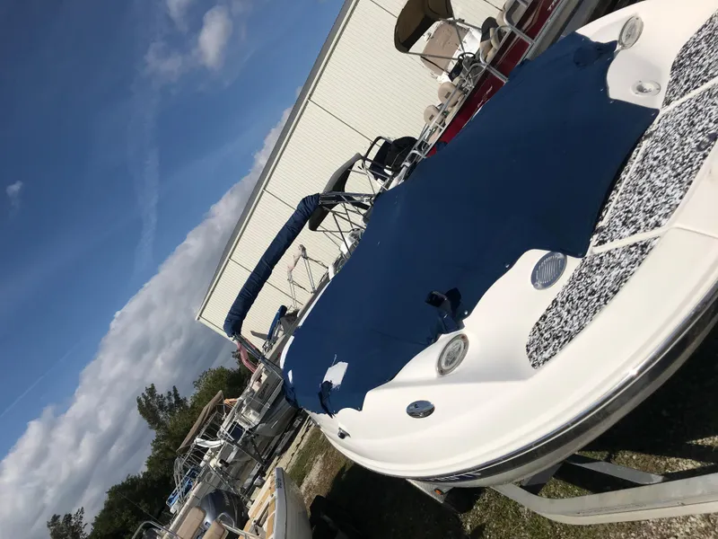 Slide: The Image of 2005 Chaparral Sunesta 252 boat with blue cover, parked outdoors near other boats. - 8