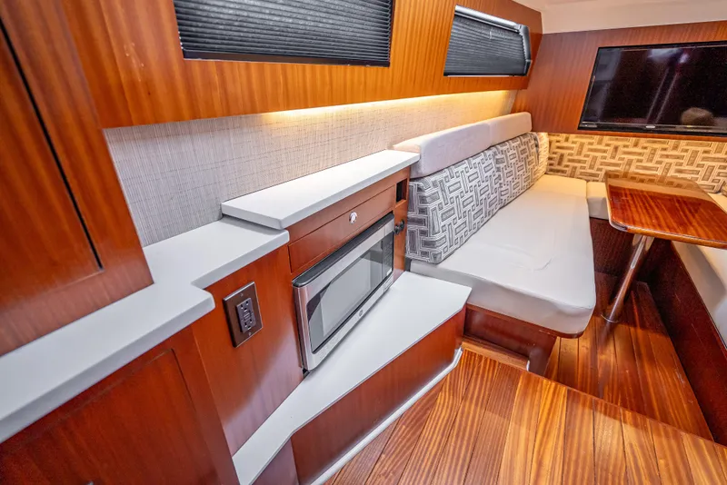 Slide: The Image of 2022 Pursuit 428S interior with modern seating, wood finishes, and built-in microwave. - 25