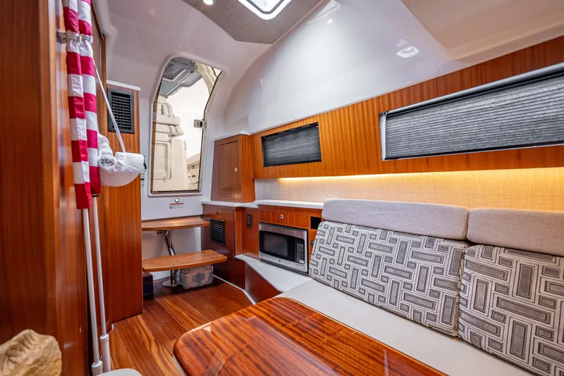 Slide: The Image of Interior of 2022 Pursuit 428S boat with modern wood finishes and cozy seating. - 27