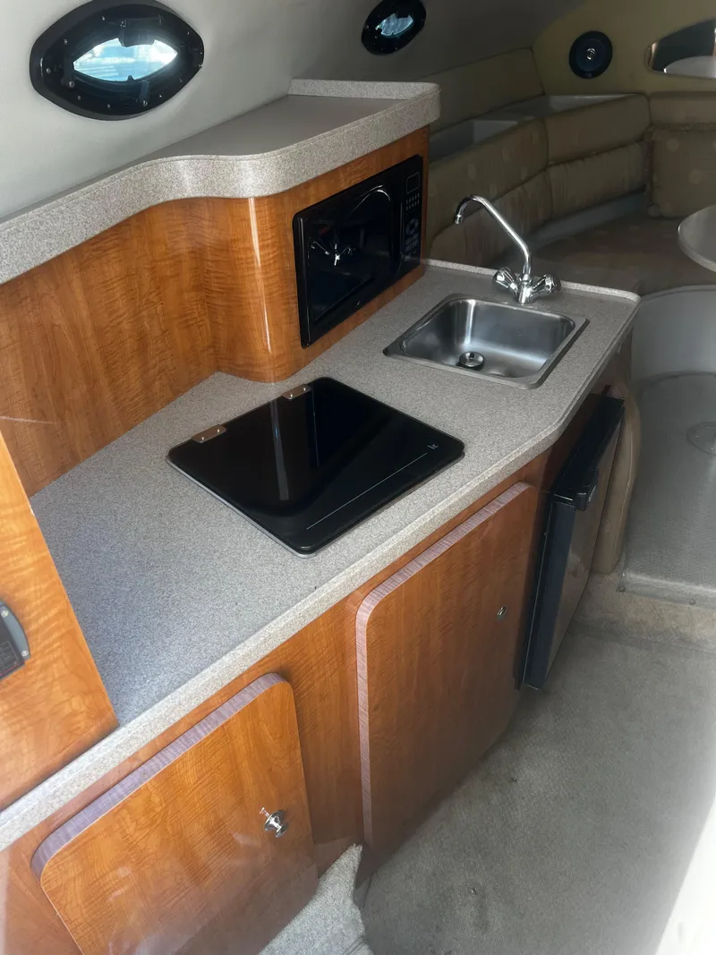 Slide: The Image of 2004 Regal 2665 Commodore Express boat interior kitchen with sink, stove, and microwave. - 18