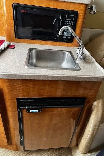 Slide: The Image of 2004 Regal 2665 Commodore Express kitchenette with sink, microwave, and mini fridge. - 19