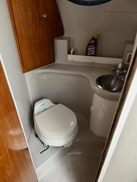 Slide: The Image of 2004 Regal 2665 Commodore Express boat bathroom with toilet, sink, and storage cabinet. - 23