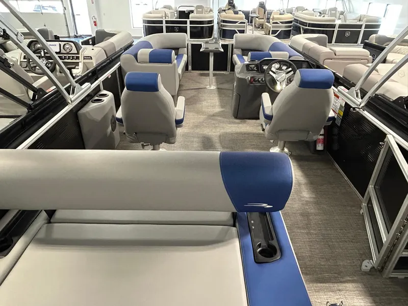 Slide: The Image of 2024 Bennington 22SSB pontoon boat interior with blue and gray seating, steering console, and spacious layout. - 14