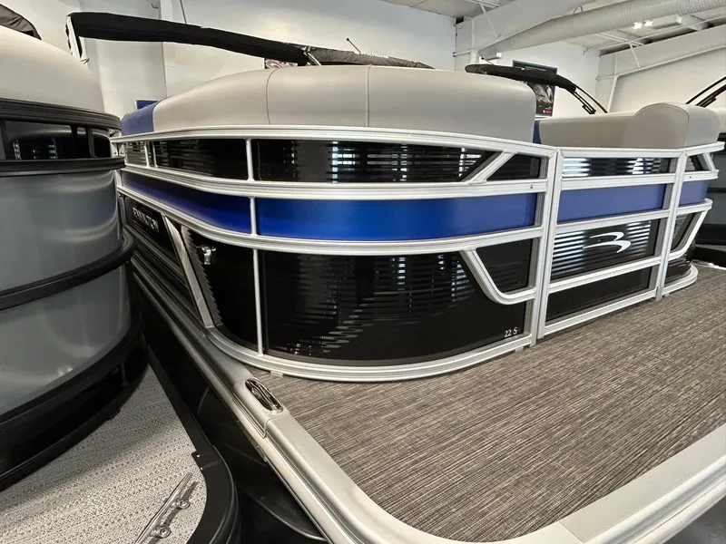 Slide: The Image of 2024 Bennington 22SSB pontoon boat, sleek design with blue and black accents, in showroom. - 2