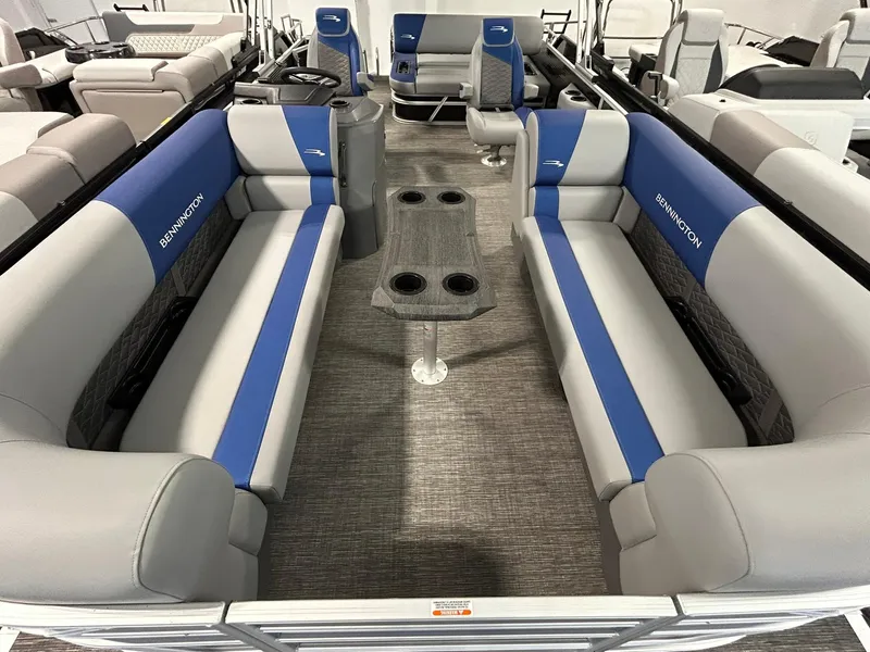 Slide: The Image of 2024 Bennington 22SSB pontoon boat interior with gray and blue seating and central table. - 3