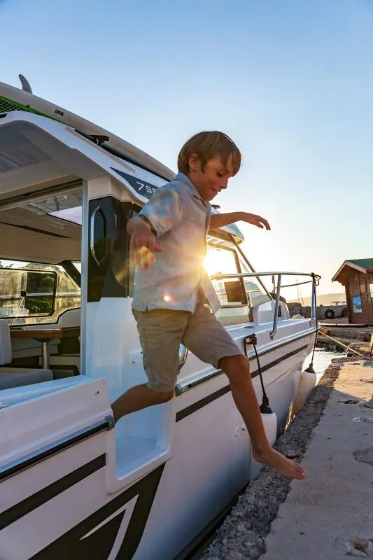 Slide: The Image of Child jumping off 2024 Jeanneau NC 795 Weekender S2 boat at sunset. - 39