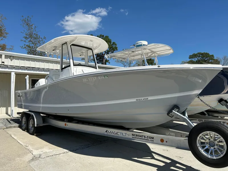 Slide: The Image of 2020 Regulator 26XO boat on trailer, parked outdoors under clear blue sky. - 16