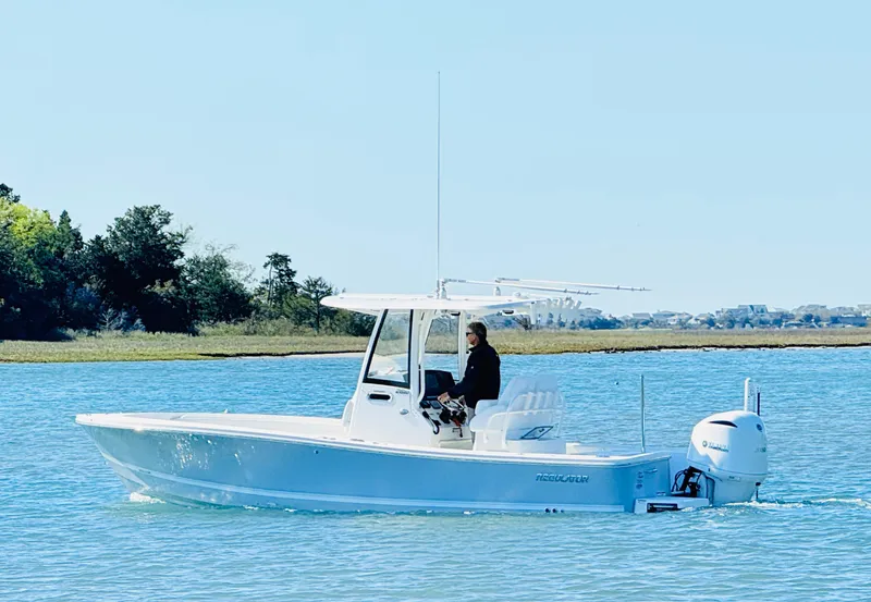 Slide: The Image of 2020 Regulator 26XO boat cruising on calm water with scenic background. - 5