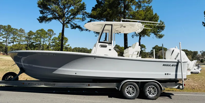 Slide: The Image of 2020 Regulator 26XO boat on trailer, parked outdoors with trees in background. - 6