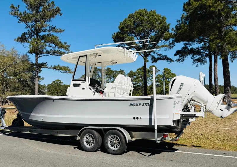 Slide: The Image of 2020 Regulator 26XO boat on trailer, parked outdoors with trees in the background. - 7