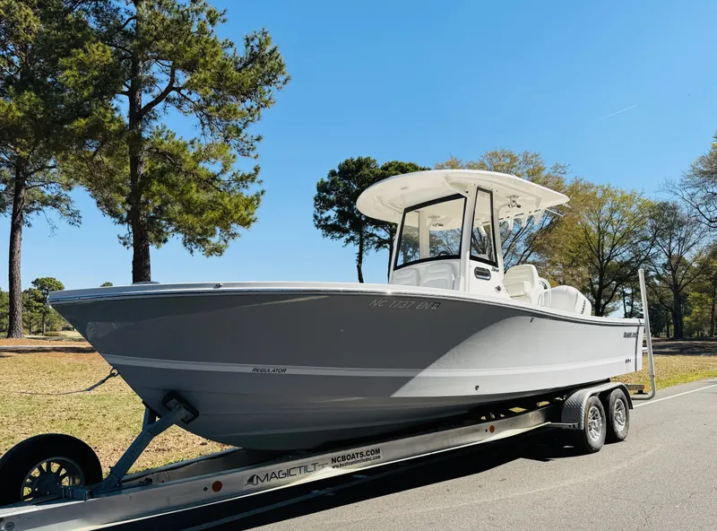 Slide: The Image of 2020 Regulator 26XO boat on trailer, parked outdoors with trees in background. - 8