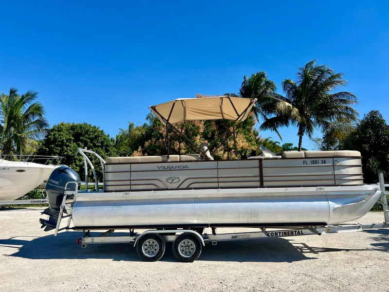 Slide: The Image of 2016 Crest Veranda V2275RC pontoon boat on a trailer with palm trees in the background. - 3