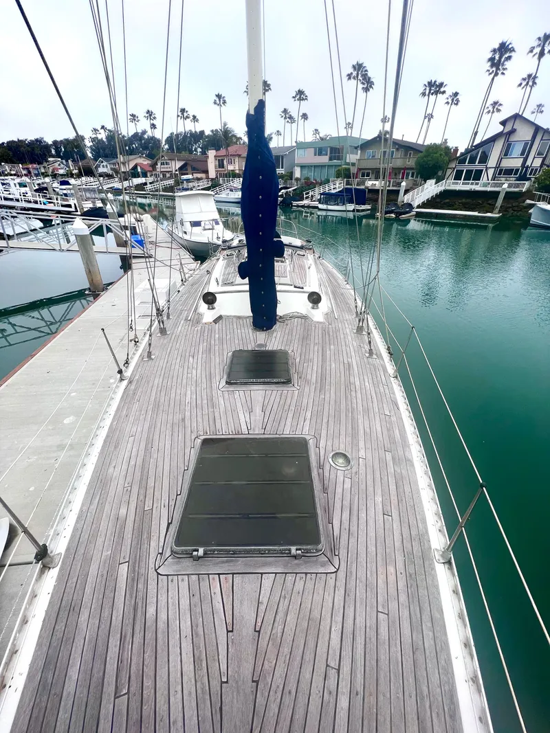 Slide: The Image of 1980 Lafitte 44 sailboat docked in a marina, showcasing wooden deck and calm waters. - 12