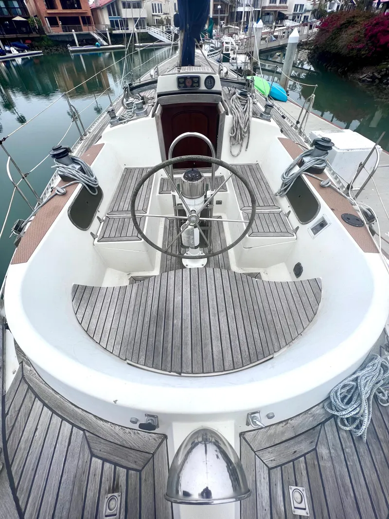 Slide: The Image of 1980 Lafitte 44 sailboat cockpit with wooden deck and steering wheel, docked in a marina. - 16