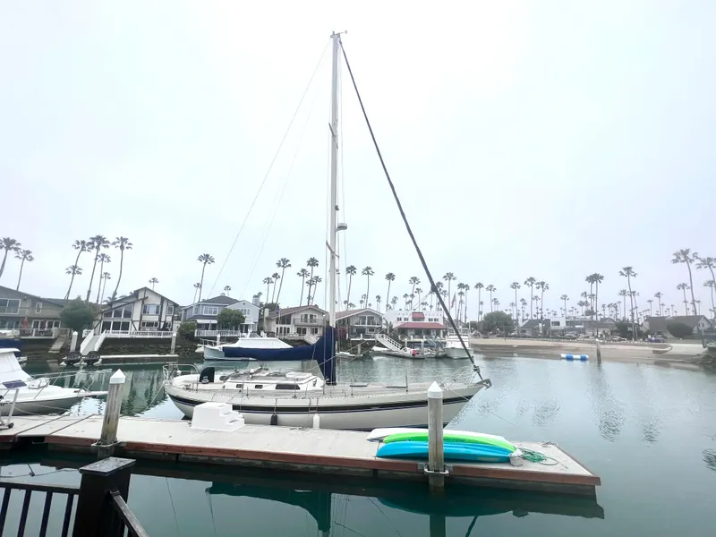 Slide: The Image of 1980 Lafitte 44 sailboat docked in a serene marina with palm trees. - 6