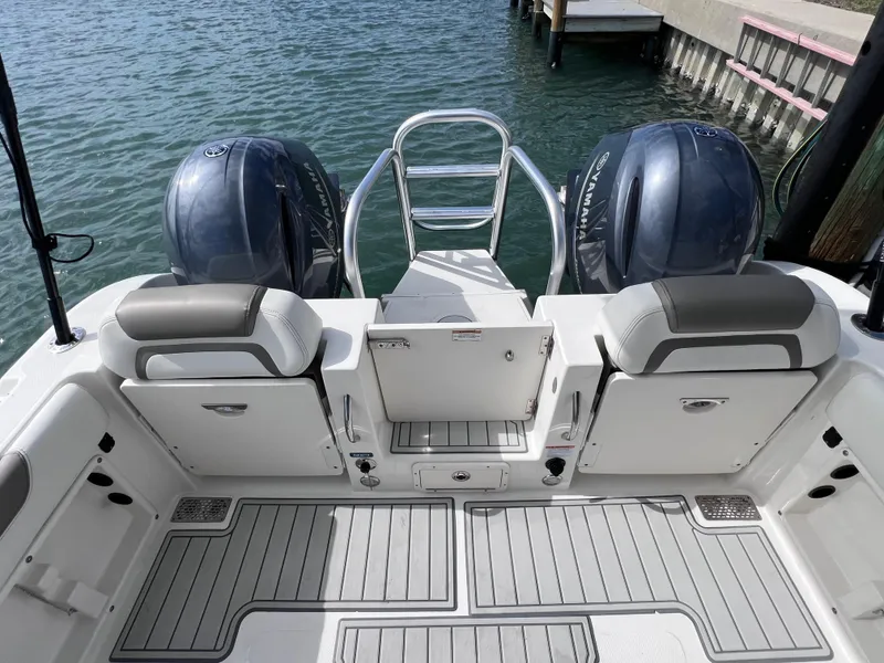 Slide: The Image of 2019 World Cat 255 DC boat interior with seating and table, docked by palm trees. - 23