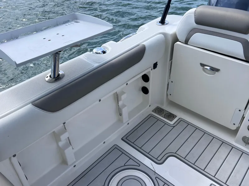 Slide: The Image of 2019 World Cat 255 DC boat interior with spacious seating and table, docked by clear water. - 25