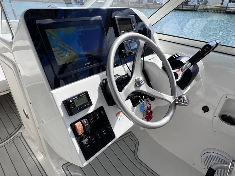 Slide: The Image of 2019 World Cat 255 DC boat interior with seating, overlooking calm waters and docked boats. - 50