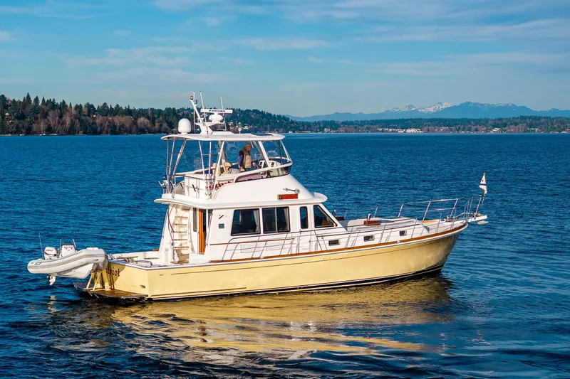 Slide: The Image of 2007 Grand Banks 47 Eastbay FB yacht cruising on a serene lake with mountain backdrop. - 73