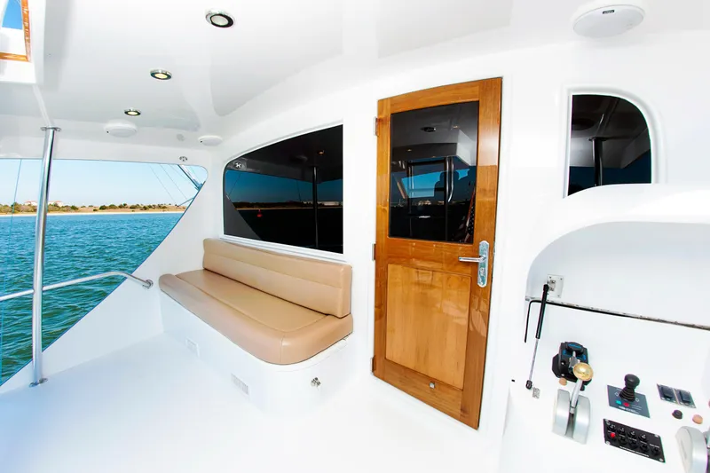 Slide: The Image of Buddy Davis 78 yacht interior, featuring a wooden door, cushioned seating, and control panel, 2000 model. - 3