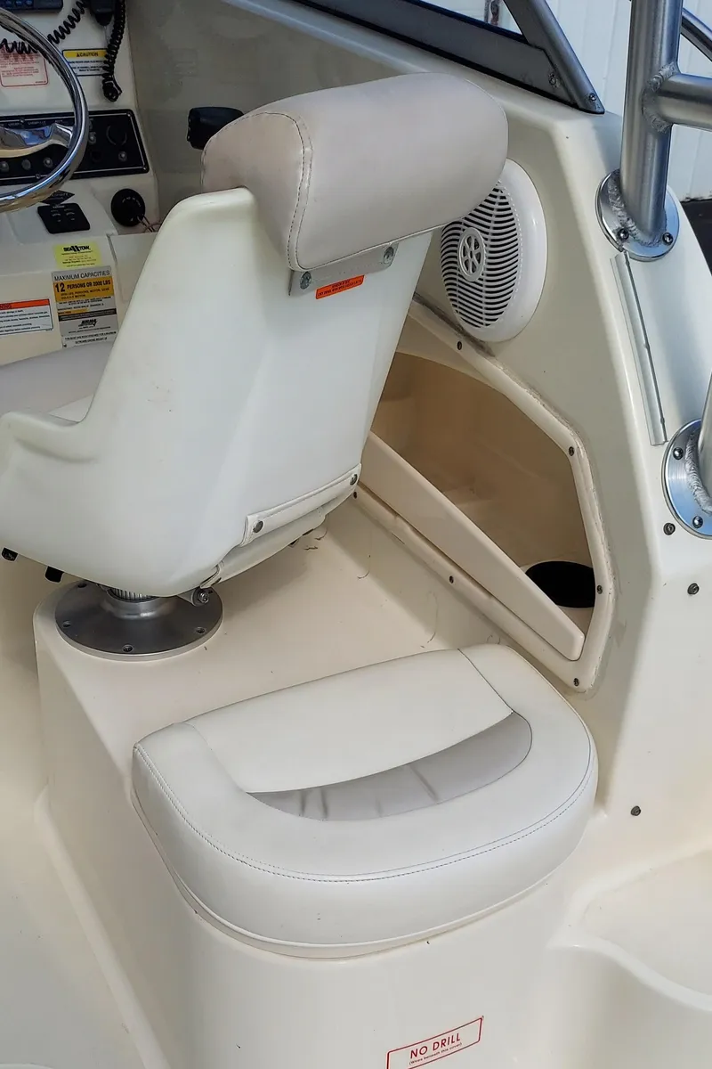 Slide: The Image of 2006 Boston Whaler 235 Conquest boat interior with white seating and dashboard. - 16