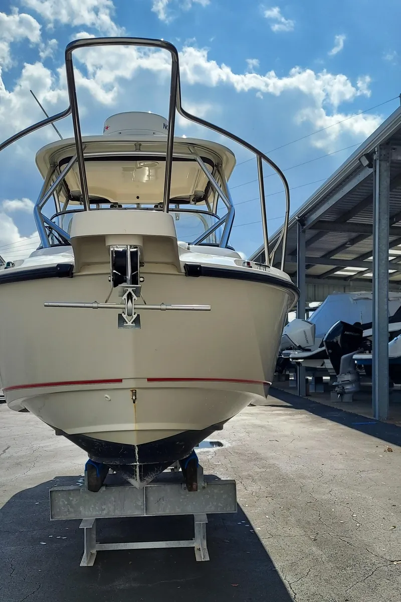 Slide: The Image of 2006 Boston Whaler 235 Conquest boat in a marina under a blue sky. - 4