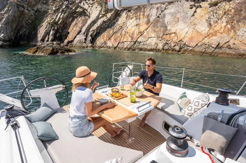 Slide: The Image of Couple dining on the deck of a 2024 Beneteau Oceanis 37.1 sailboat near rocky cliffs. - 8