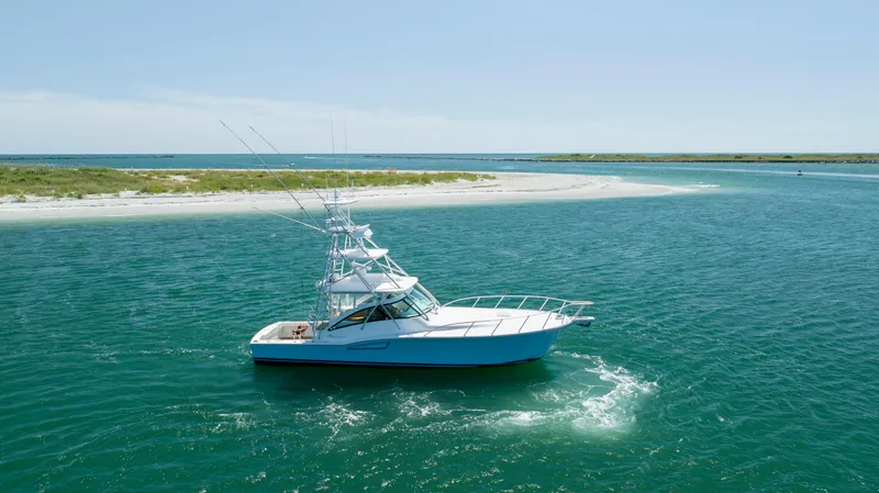 Slide: The Image of 2019 Albemarle 410 Express Fisherman boat cruising near a sandy shoreline. - 1