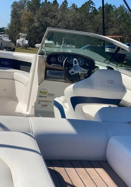 Slide: The Image of 2012 Regal 2100 boat interior with white and blue seating, steering wheel, and dashboard. - 11