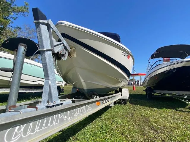 Slide: The Image of 2012 Regal 2100 boat on a trailer, parked on grass, clear blue sky. - 3