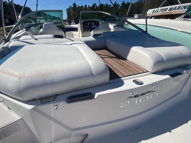 Slide: The Image of 2012 Regal 2100 boat with white seating and wooden deck. - 6