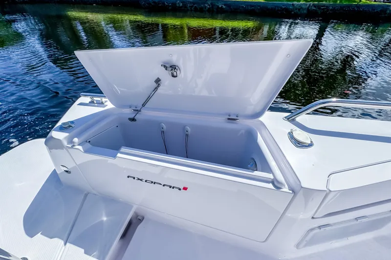 Slide: The Image of 2024 Axopar 37 Sun Top boat with open storage compartment by the water. - 11