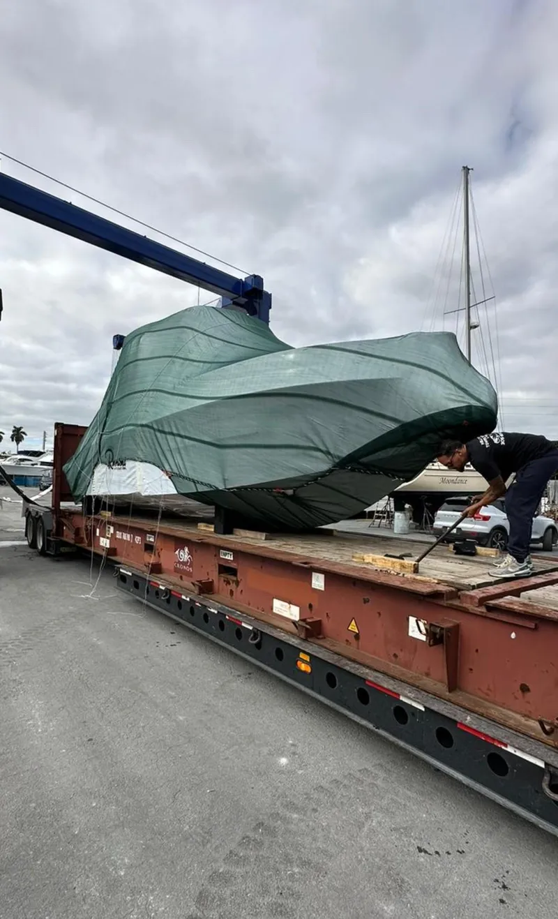 Slide: The Image of 2024 Ranieri 275 SL boat being transported on a flatbed trailer, covered with a green tarp. - 6