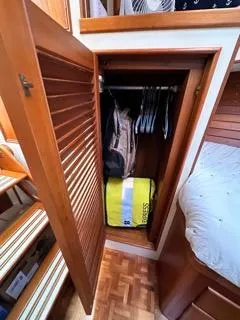 Slide: The Image of Wooden closet on 1996 Grand Banks Classic boat with hanging clothes and yellow bag. - 13