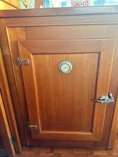 Slide: The Image of Wooden cabinet door with a round gauge, aboard a 1996 Grand Banks Classic. - 37