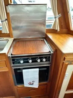 Slide: The Image of 1996 Grand Banks Classic yacht kitchen with stove, wooden cabinetry, and curtains. - 39