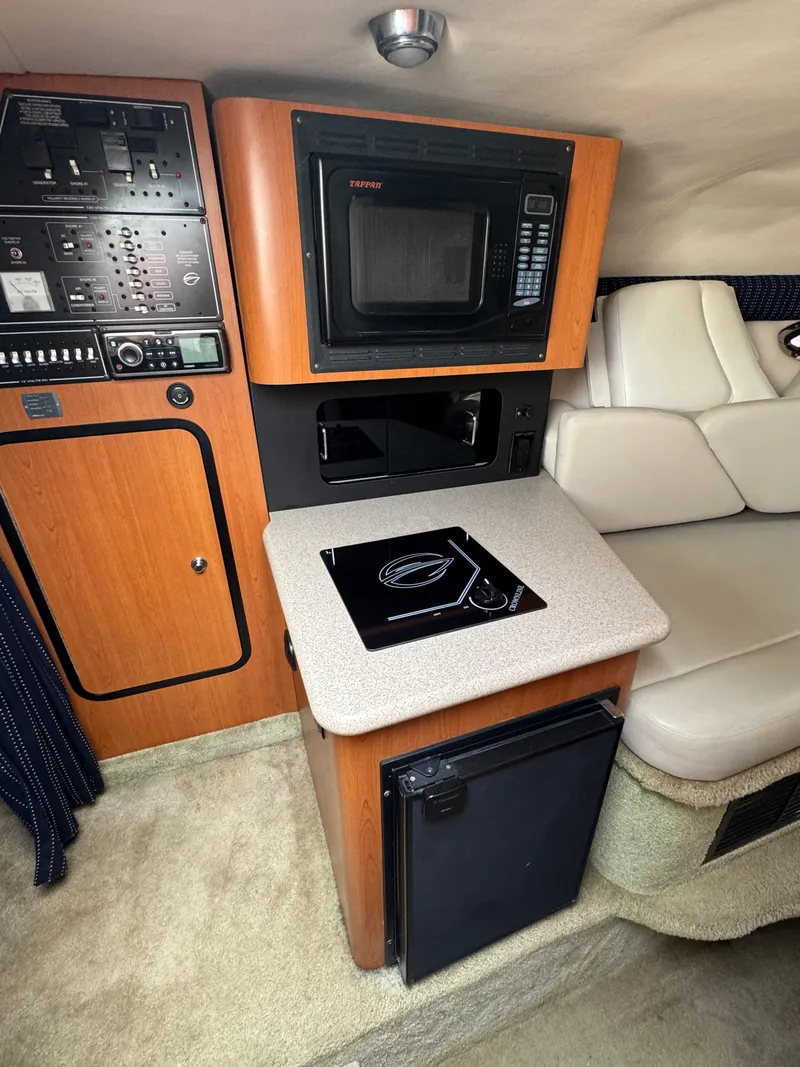 Slide: The Image of 2008 Crownline 315 SCR cabin interior with kitchenette, featuring microwave, stove, and seating. - 18