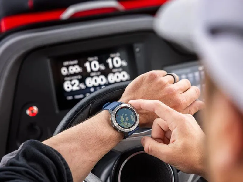 Slide: The Image of Person checking smartwatch while steering 2024 Manitou XT 23 Split Rear Sport boat. - 30