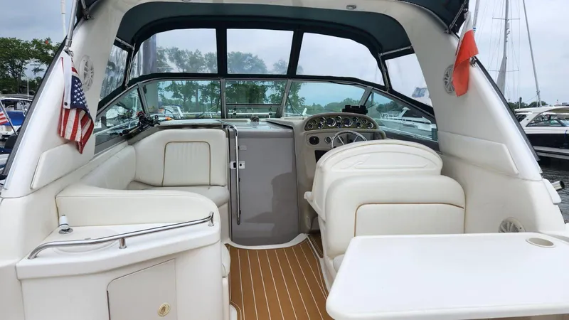 Slide: The Image of 1999 Sea Ray 290 Sundancer boat interior with seating and dashboard, docked at marina. - 2