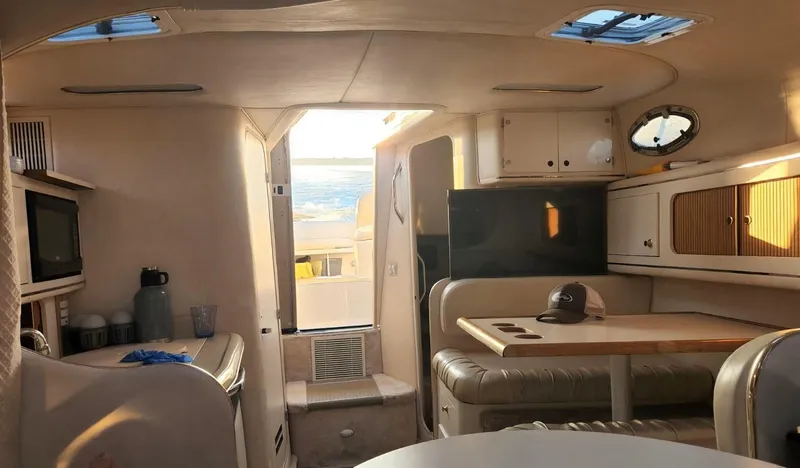 Slide: The Image of 1999 Sea Ray 290 Sundancer cabin interior with seating, table, and kitchenette. - 9