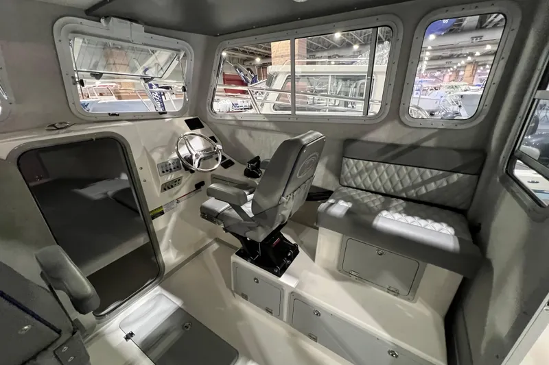 Slide: The Image of Interior of 2025 Defiance 260 Admiral boat, featuring helm, seating, and windows. - 11