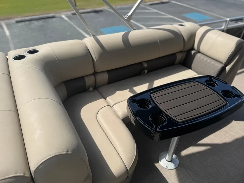 Slide: The Image of 2024 Sun Tracker Fishin' Barge 20 DLX interior with beige seating and black table. - 8