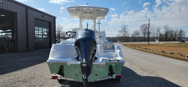 Slide: The Image of 2024 Sea Fox 248 Side Console boat with outboard motor, parked outside a warehouse. - 2