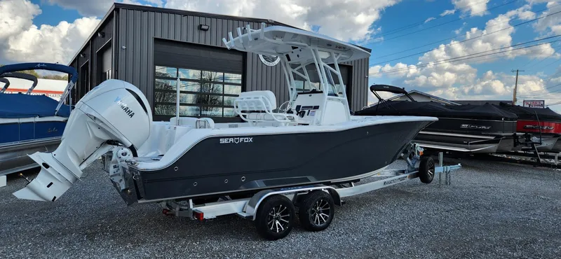 Slide: The Image of 2024 Sea Fox 248 Commander boat on trailer, parked outside a building under a cloudy sky. - 3