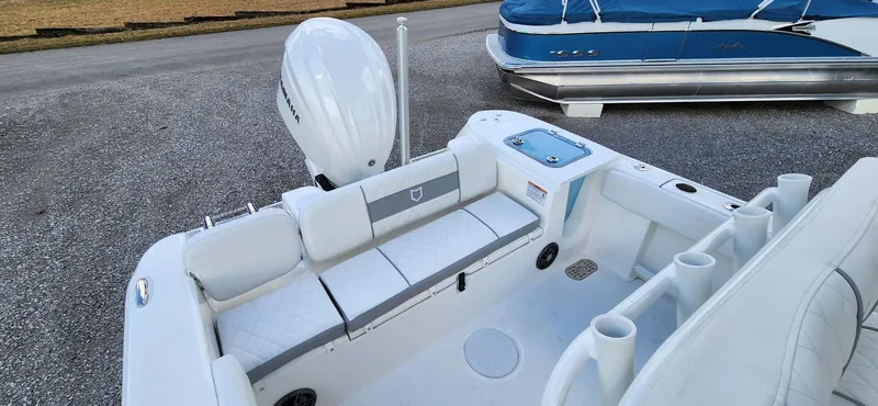 Slide: The Image of 2024 Sea Fox 248 Commander boat interior with seating and motor, parked on gravel. - 6