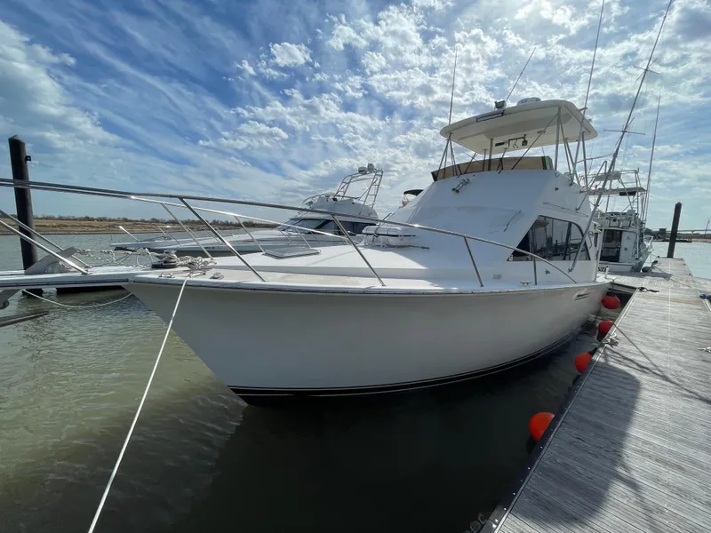 The Image of 1985 Ocean 38 Super Sport yacht docked under a partly cloudy sky. - 0