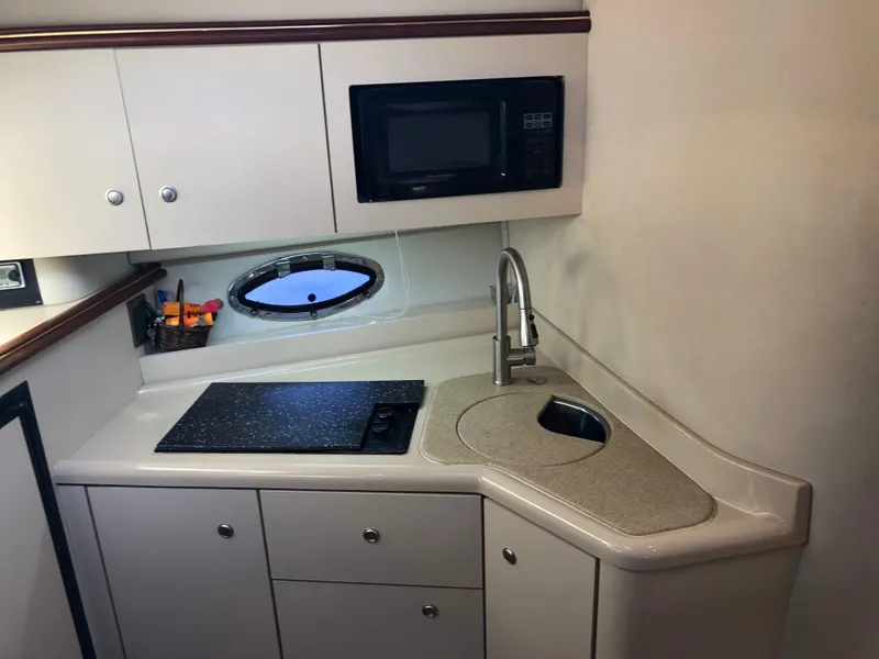 Slide: The Image of Compact kitchen area in 2000 Cruisers Yachts 3375 Express with sink, stove, and microwave. - 14
