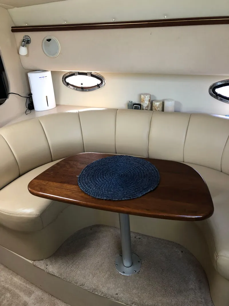 Slide: The Image of 2000 Cruisers Yachts 3375 Express interior dining area with leather seating and wooden table. - 13