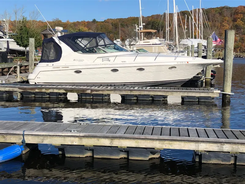 Slide: The Image of 2000 Cruisers Yachts 3375 Express docked at a marina with fall foliage in the background. - 2